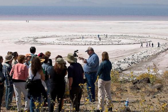 Bob Phillips, the contractor who built the Jetty for Robert Smithson, addresses the group, with the high and dry Jetty, encrusted in salt beyond. CLUI photo by Steve Rowell